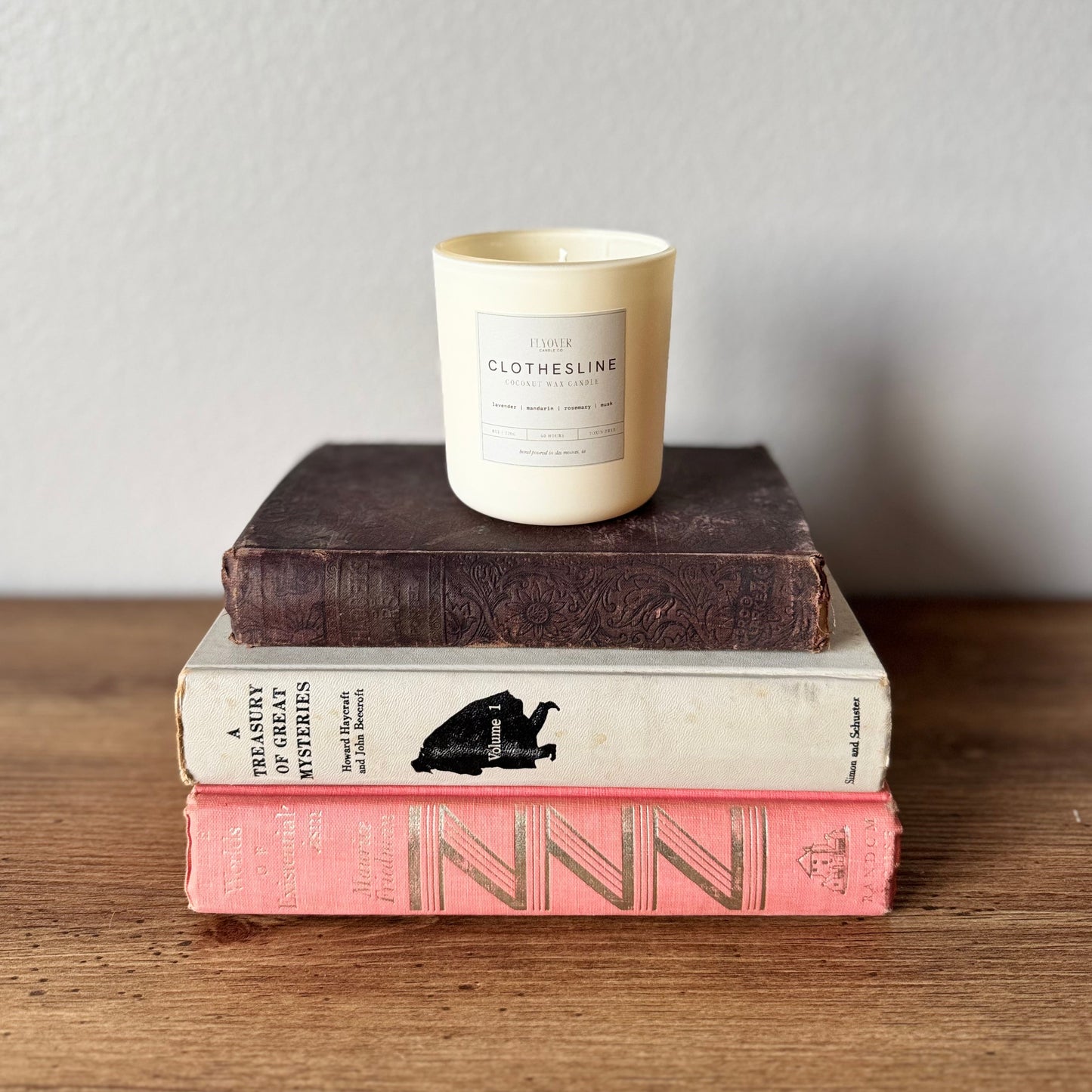 Stack of books with a candle on top against a plain background