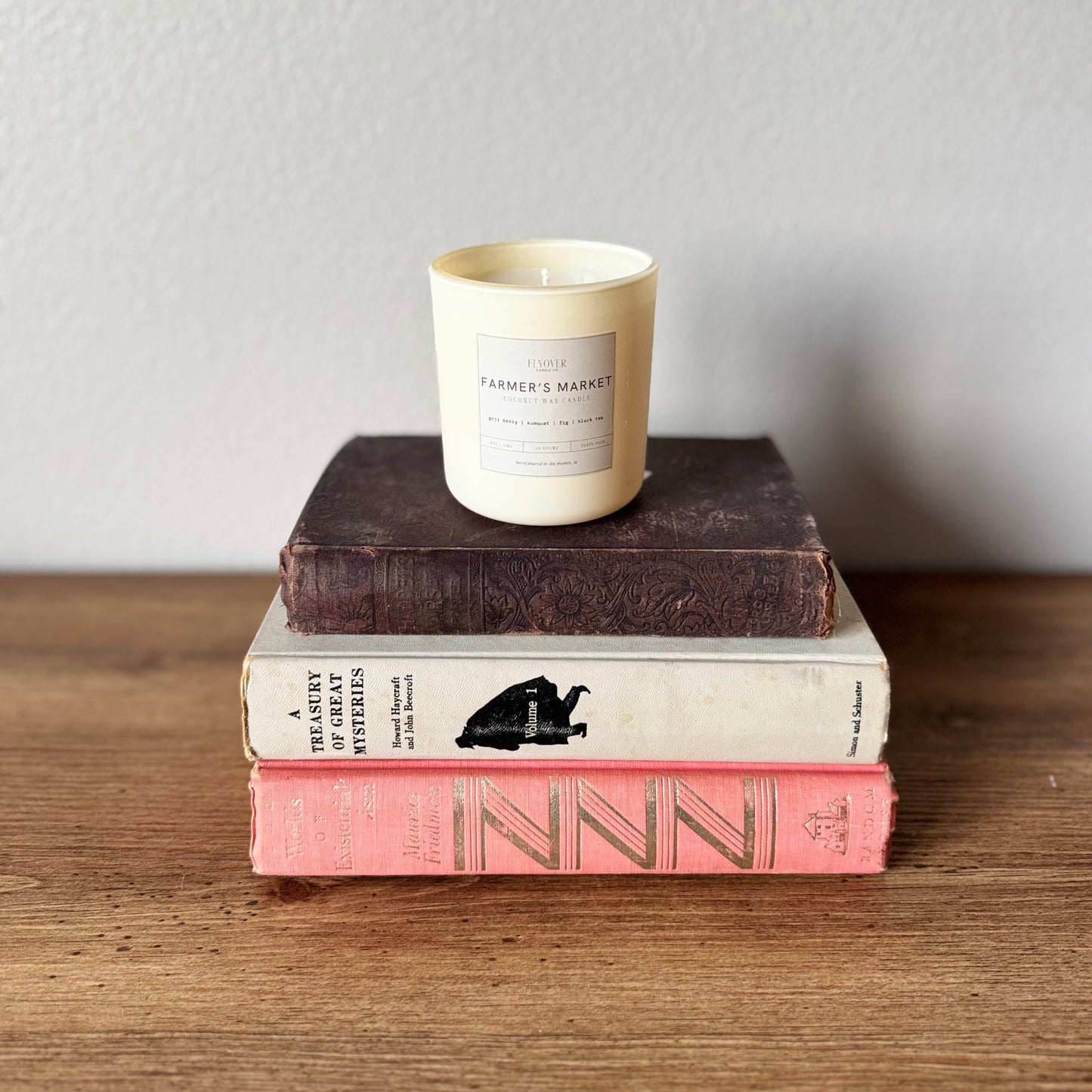 Stack of books with a candle on top against a plain background
