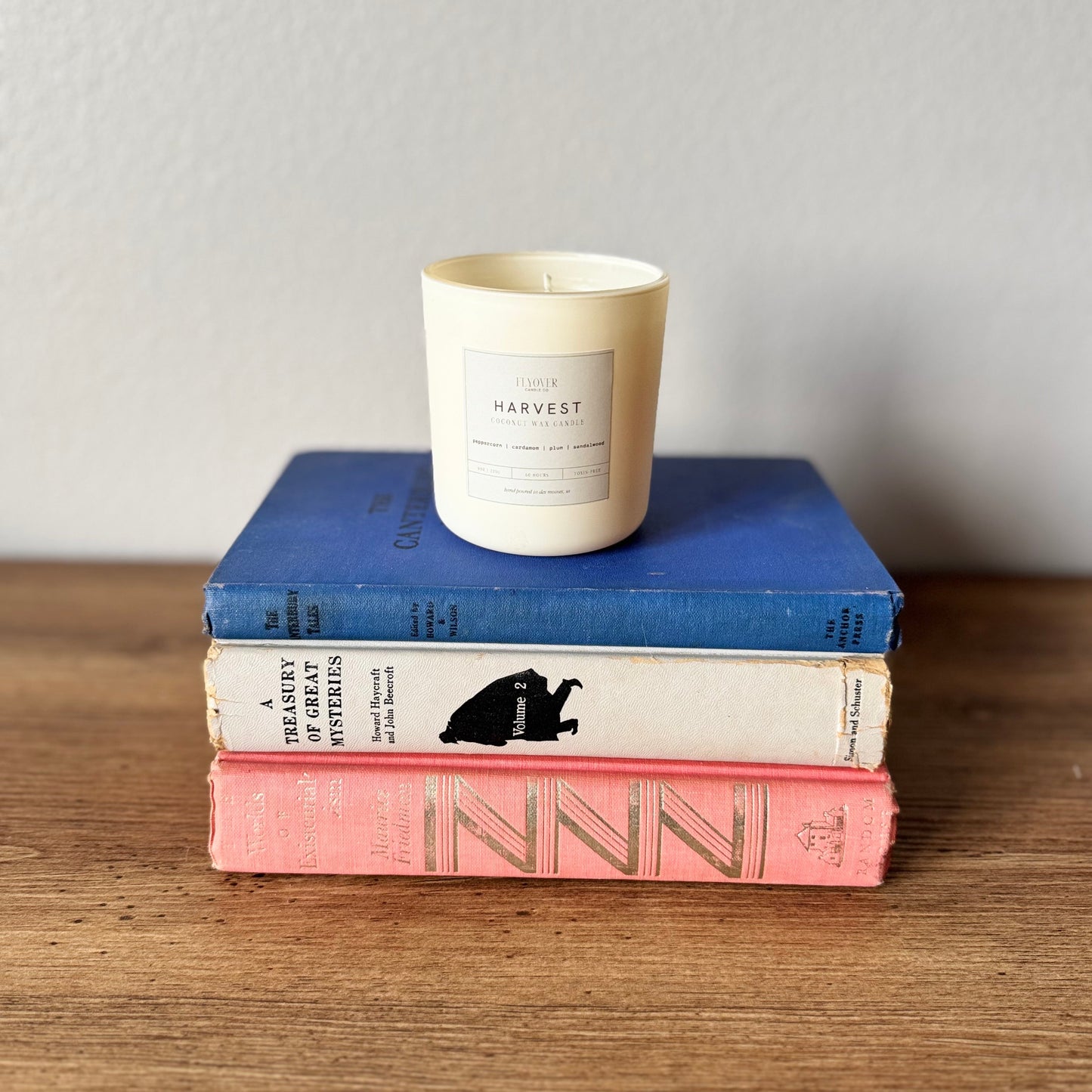 Stack of books with a candle on top against a plain background