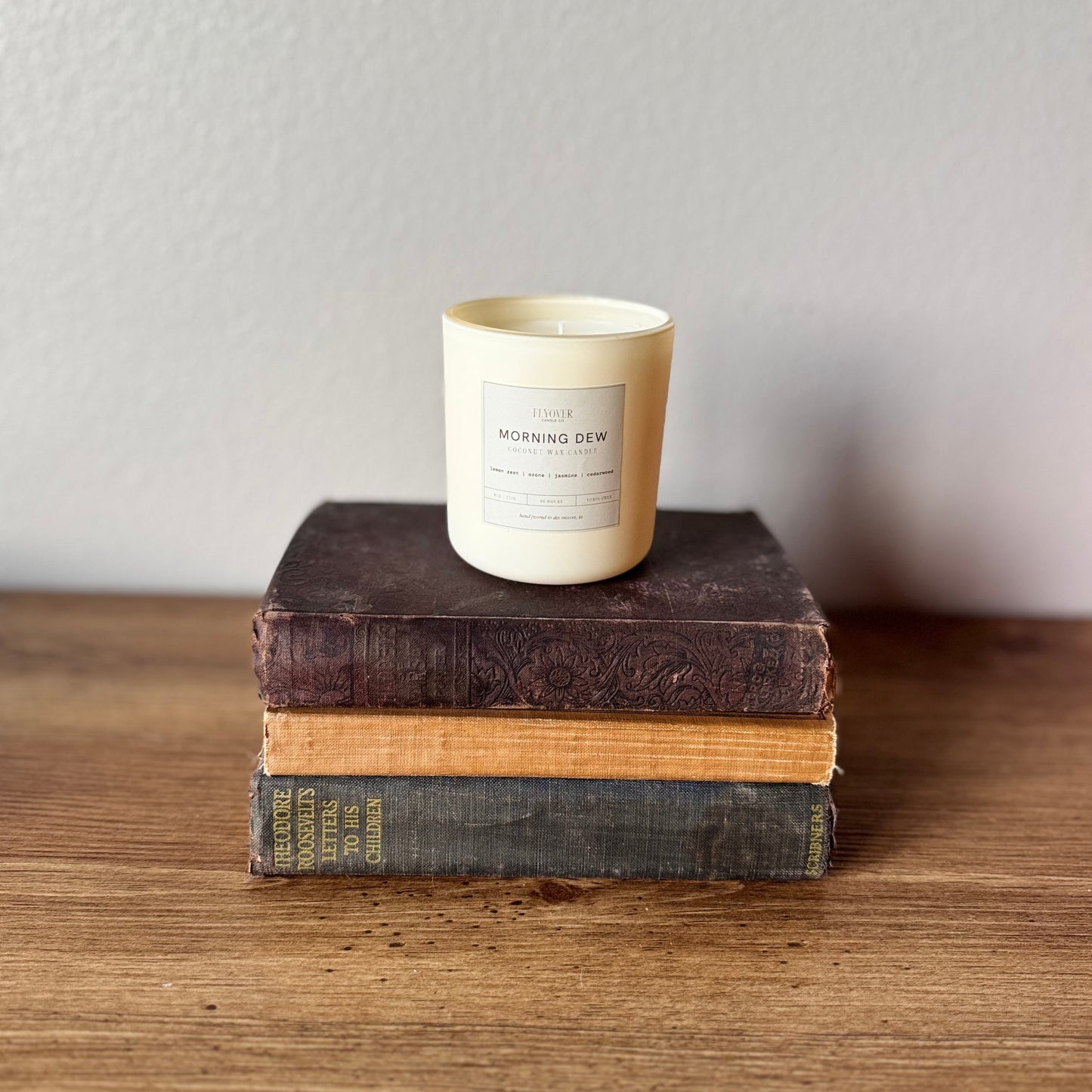 Candle on a stack of books with a neutral background
