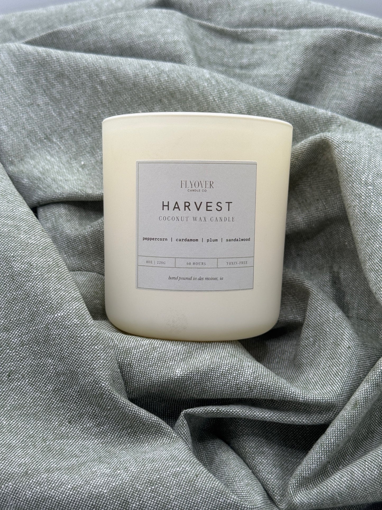 Candle labeled 'Harvest' on a textured gray fabric background