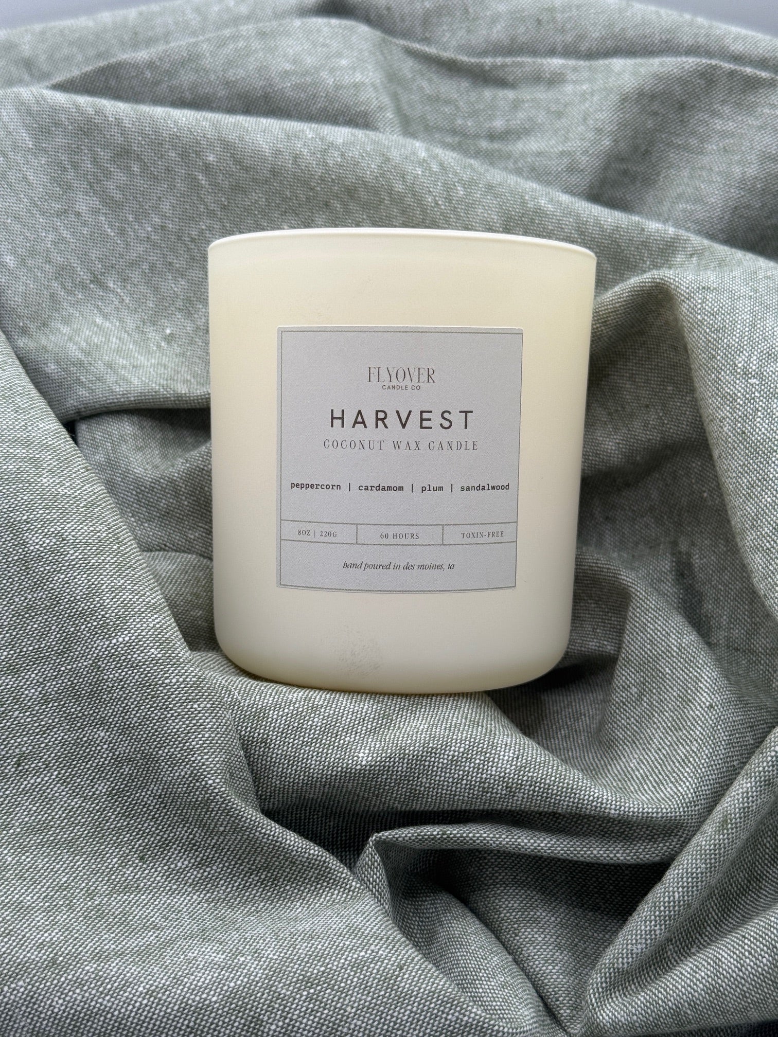 Candle labeled 'Harvest' on a textured gray fabric background