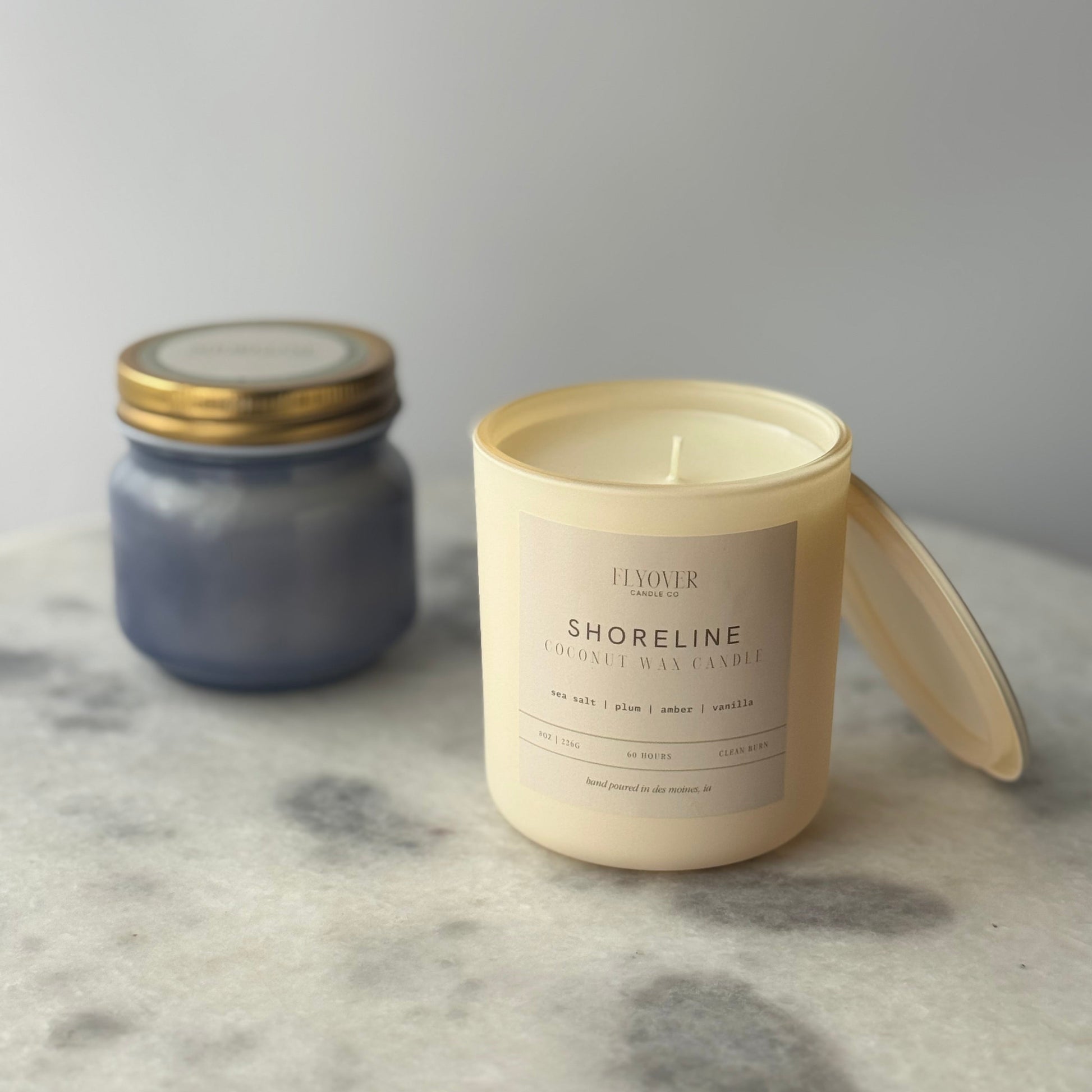 Two candles on a marble surface with a neutral background