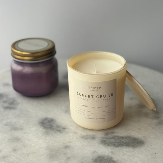 Two candles, one purple and one labeled 'Sunset Cruise', on a marble surface.