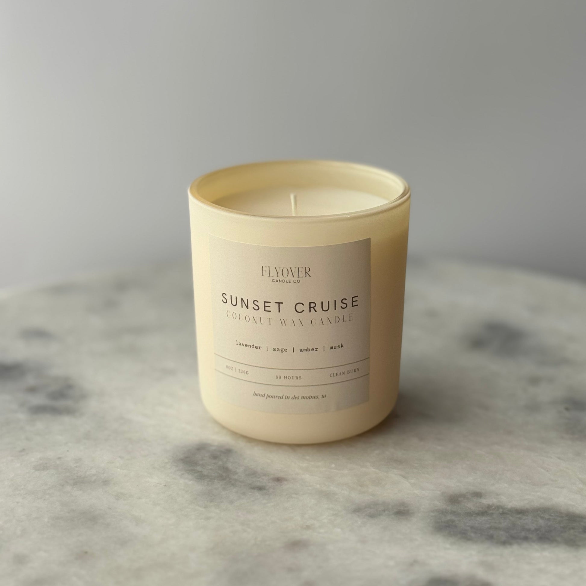Candle labeled 'Sunset Cruise' on a marble surface with a gray background