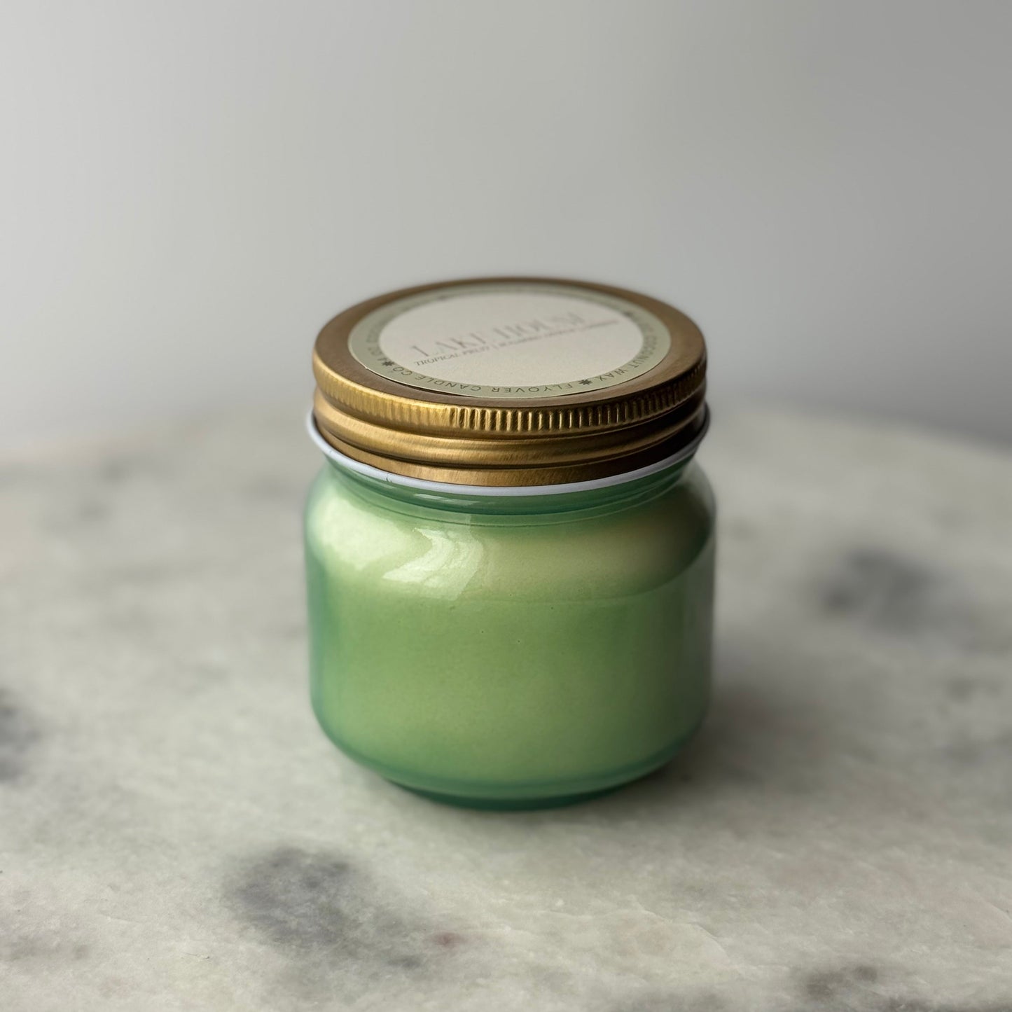 Green jar with a gold lid on a marble surface