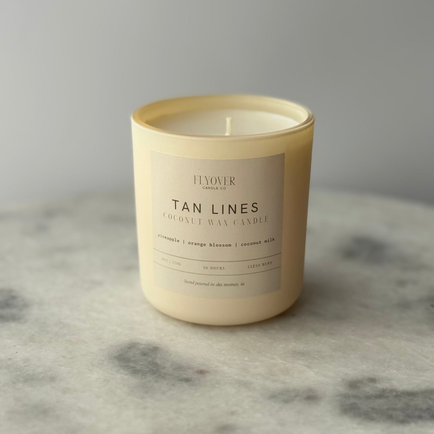 Tan candle with a label on a marble surface