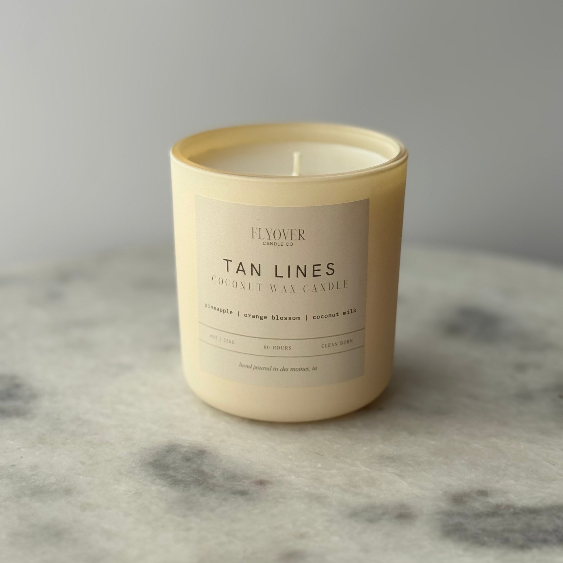 Tan candle with a label on a marble surface