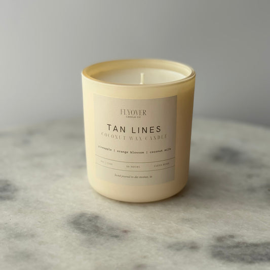 Tan candle with a label on a marble surface